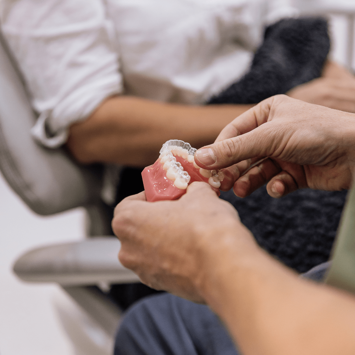 Hands holding dental model with braces and clear aligners, showcasing orthodontic treatment options at our Pomona clinic.