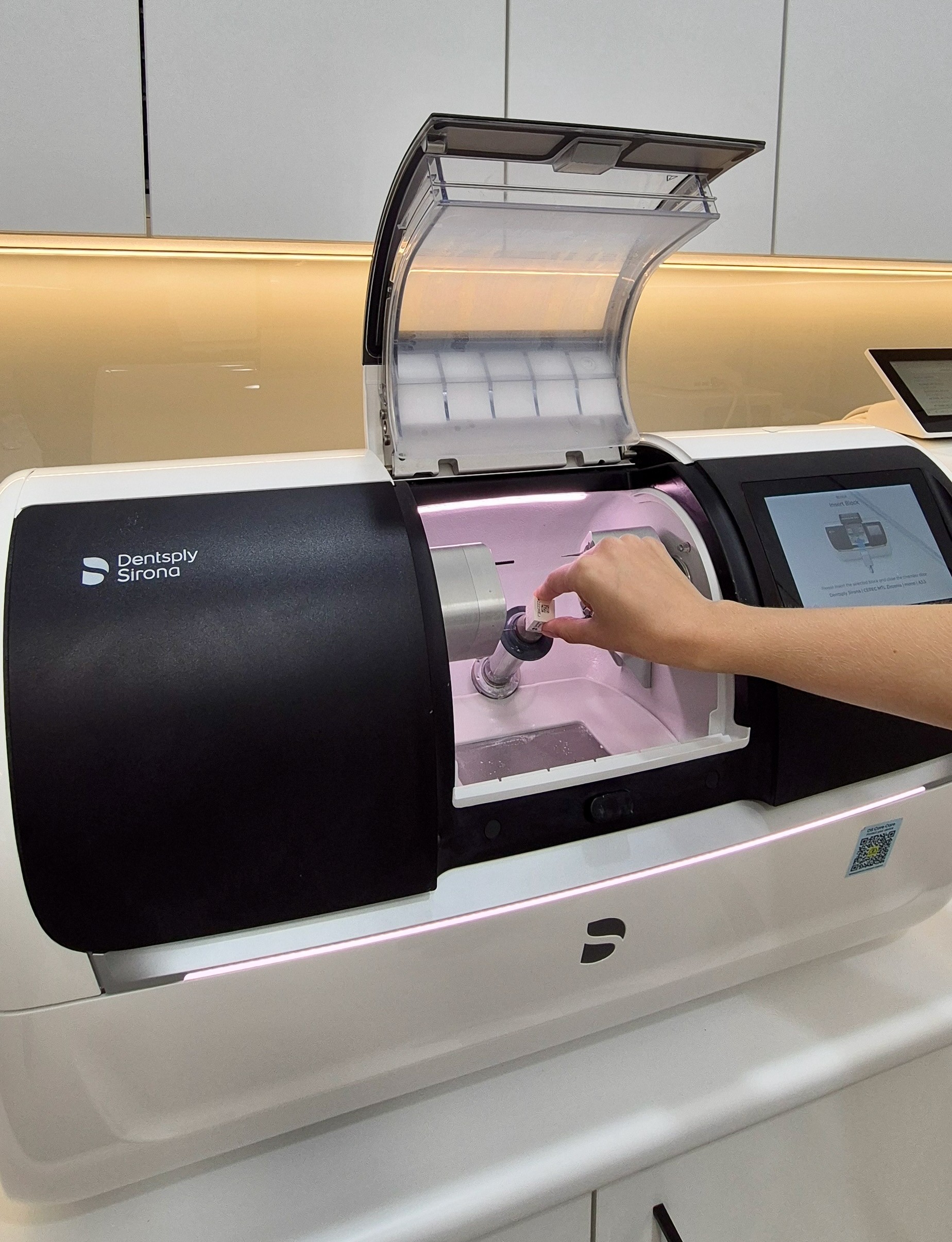 Dental practitioner loading a CEREC Primemill milling machine for same-day crown fabrication at our clinic.